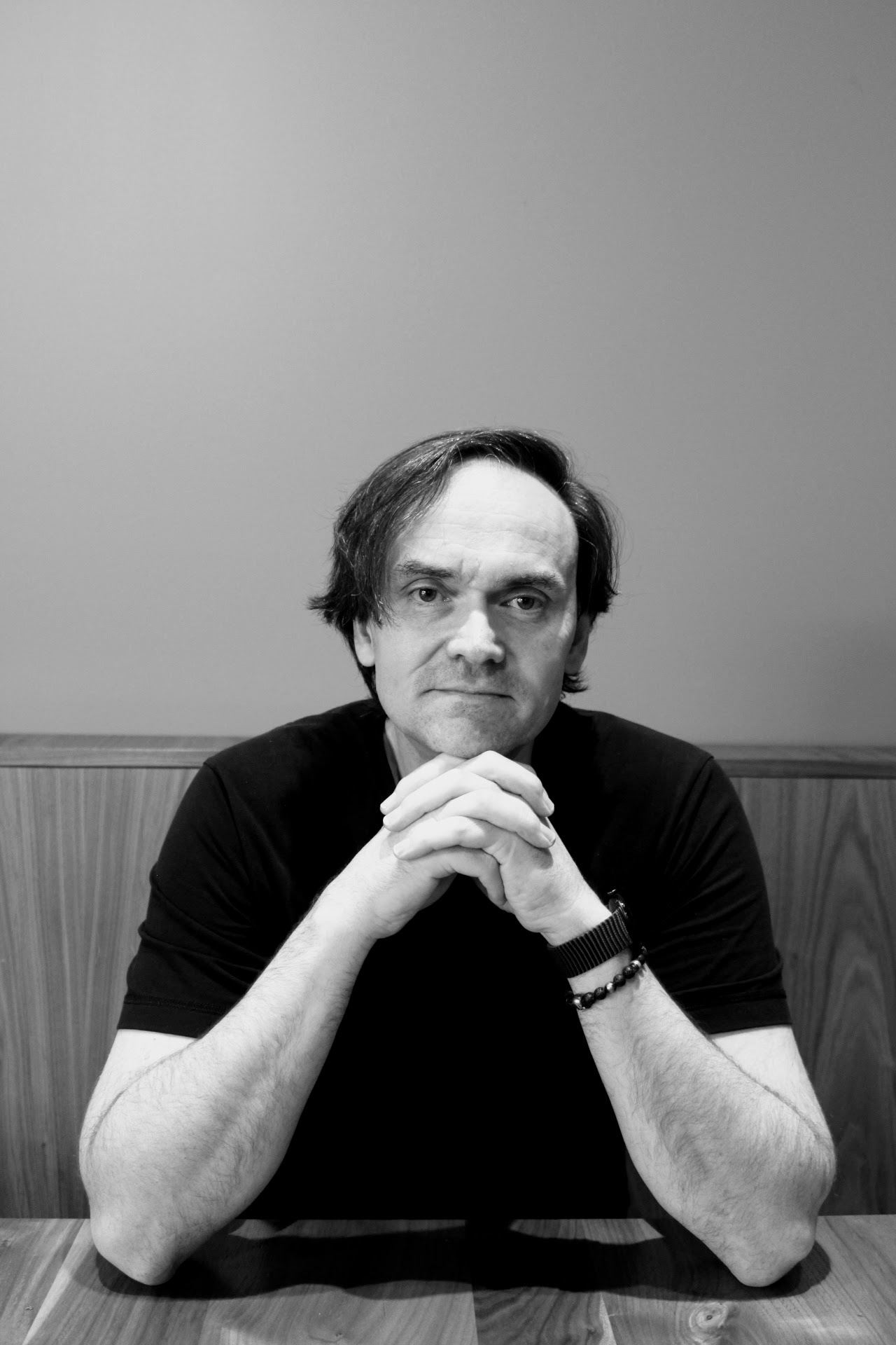 Torsten Schulz, in black and white, seated at a restaurant table with his hands folded.